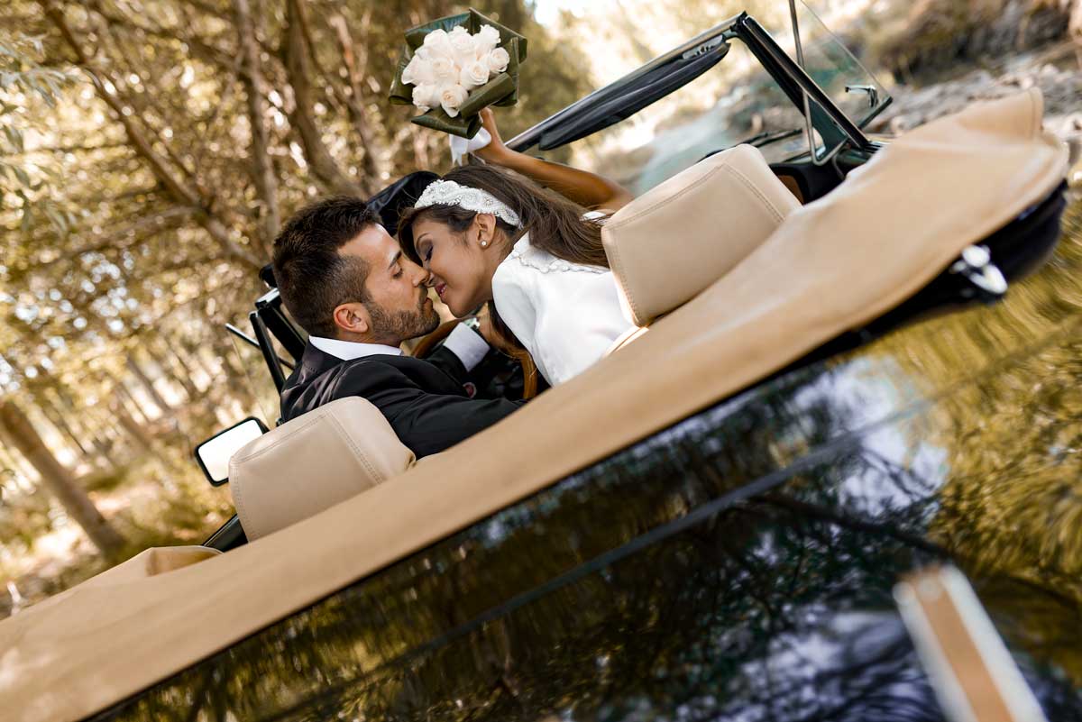 Novios sobre un coche descapotable alquilado para la boda en Barcelona