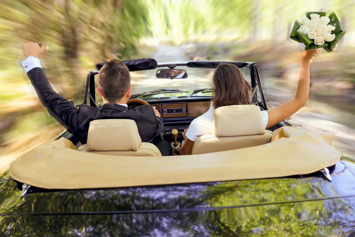 Newlyweds on their honeymoon in a rented convertible car in Barcelona