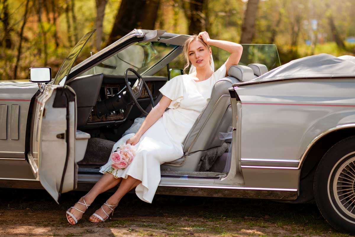 Bride sitting on top of a convertible wedding car